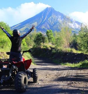 คนบนรถสี่ล้อบนถนนดินยกแขนขึ้น