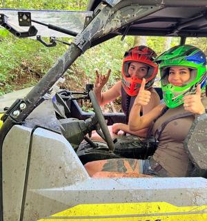 two people giving the thumbs up while sitting in the front seat of a atv