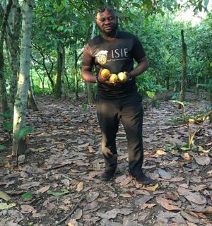 一名男子站在树林里,手里拿着一串水果