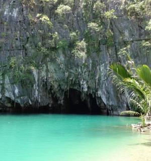 a pool of blue water in front of a limestone cave