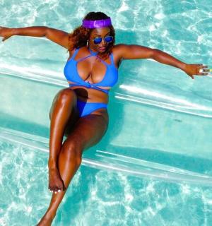 一位身穿蓝色泳衣的女子坐在游泳池的木筏上