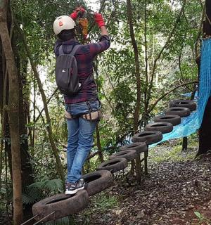 osoba stojící na visutém mostě v lese
