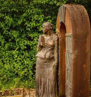 一座女性雕像矗立在石拱门旁