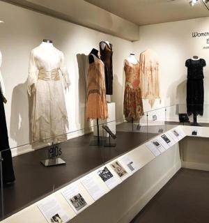 a display case in a museum with many different dresses