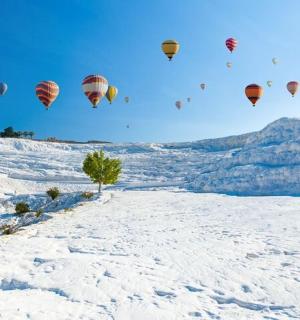 一群热气球飞过白雪覆盖的田野