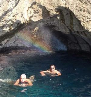 three men swimming in a cave with a rainbow