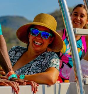 eine Frau mit Hut und Sonnenbrille sitzt auf einem Boot