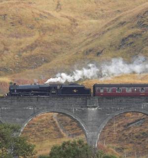 a train on a bridge with smoke coming