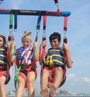 tři lidé jezdí na zipline na pláži