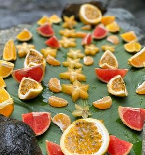 a green leaf with oranges and other fruits on it