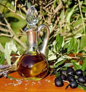 一瓶橄榄油旁边是一束黑橄榄