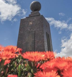 a building with a statue in the background with red flowers