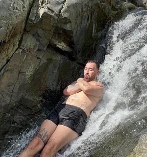 muž ležící na skále ve vodopádu