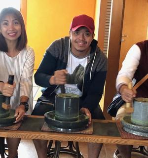 a group of three people sitting around a table with pottery
