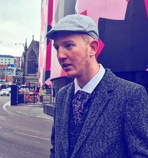 一位戴着帽子、穿着西装打着领带的男士