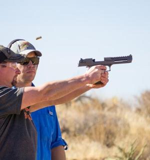 two men are holding a gun in a field