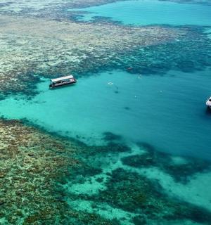 two boats in the water next to a reef