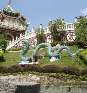 a garden with two dragon statues in front of a building