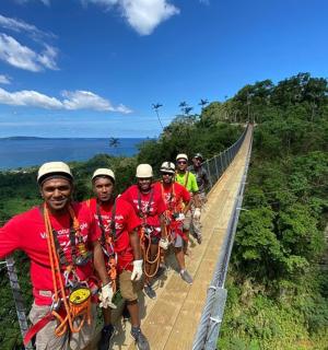 a group of men standing on a suspension bridge over a cliff