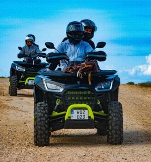 tři lidé jedoucí na čtyřkolkách po nezpevněné cestě