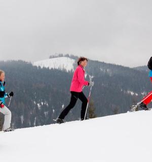 three people walking up a snow covered slope on skis