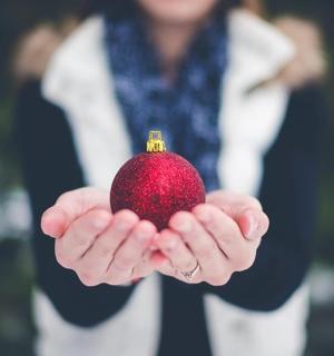 a woman holding a red ornament in her hands