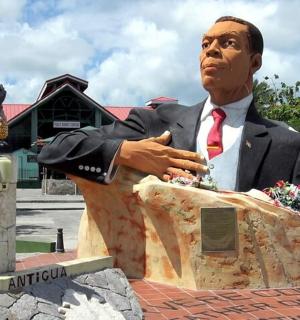 socha muže v obleku sedícího na skále