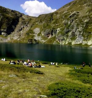 一名男子站在一座有湖的山前