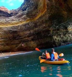 two people in a kayak in the water near a cave