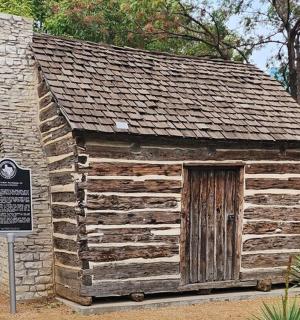a small log cabin with a sign in front of it