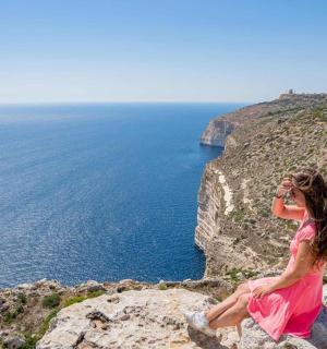 žena sedící na útesu a telefonující