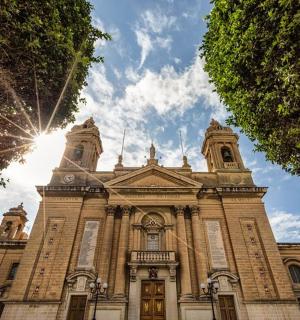 a large brick building with the sun behind it