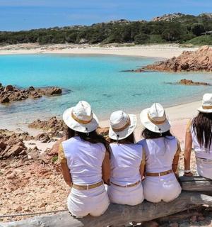 四个穿白衣服的女孩坐在海滩的长椅上
