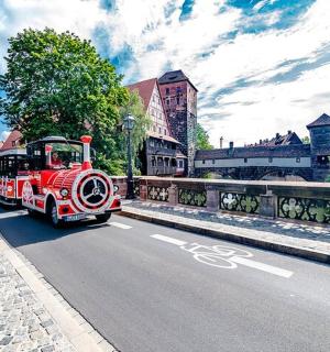 a red train driving down a street on a road