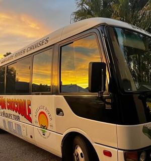 a bus parked on the side of a street with the sunset