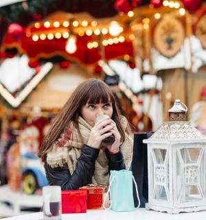 一位女士坐在桌边，手里拿着一个杯子，面前是一盏灯笼