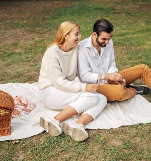 a man and woman sitting on a blanket on the grass