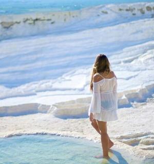 一位身穿白色连衣裙的女子站在海滩上