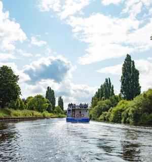 a blue boat traveling down a river with trees