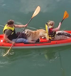两个人和一只狗在水上的皮划艇上