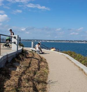 a group of people walking on a path near the water