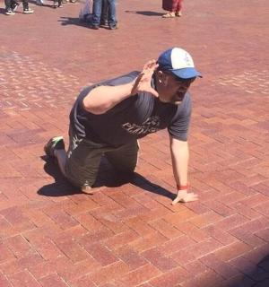 a man kneeling on the ground on a brick street