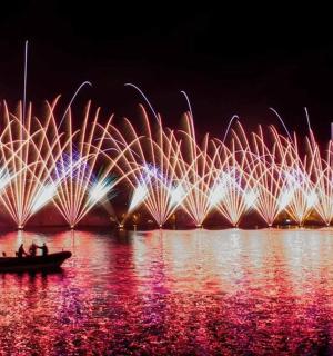 eine Gruppe von Menschen in einem Boot im Wasser mit Feuerwerk