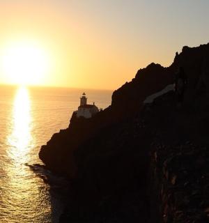 Západ slunce nad oceánem s majákem na útesu