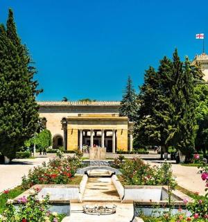 a building with a fountain in a park with flowers
