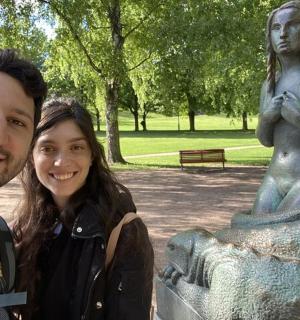 a man and a woman standing next to a statue