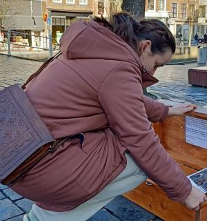 一位女士坐在长椅上,手里拿着一个包