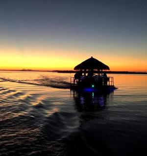 loď s chatrčí na vodě při západu slunce