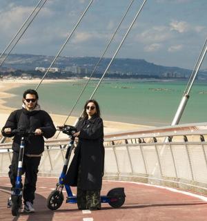 两个人骑着滑板车在海滩桥上