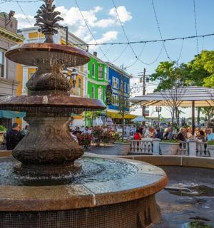a fountain in a city with people sitting at tables